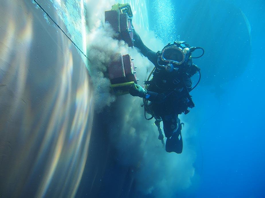 Professional diver carrying out underwater ship hull cleaning
