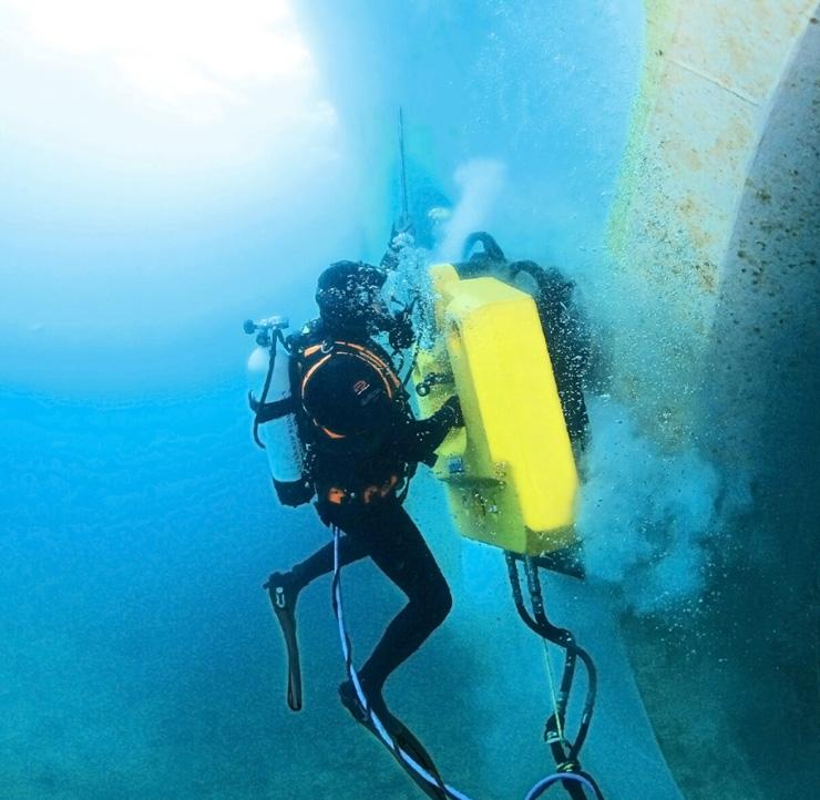 Diver cleaning marine growth from a commercial vessel hull